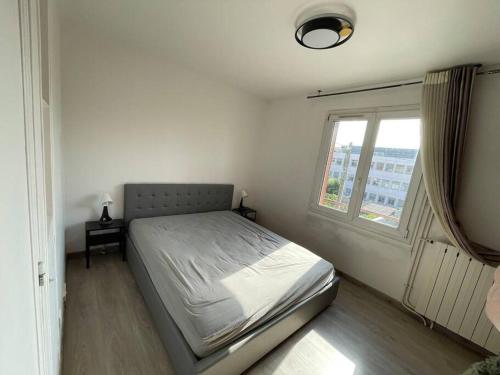 ein weißes Schlafzimmer mit einem Bett und einem Fenster in der Unterkunft Maison de ville,RER A 20 min pour Paris/Disneyland in Neuilly-sur-Marne