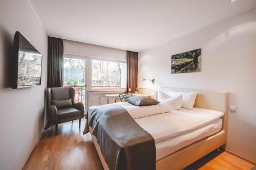 a bedroom with a bed and a chair and a window at Landidyll Hotel Restaurant Weidenbrück & SPA in Swisttal