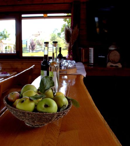 a bowl of apples on a table with bottles of wine at Brezova Poljana Lodge in Vrbovsko