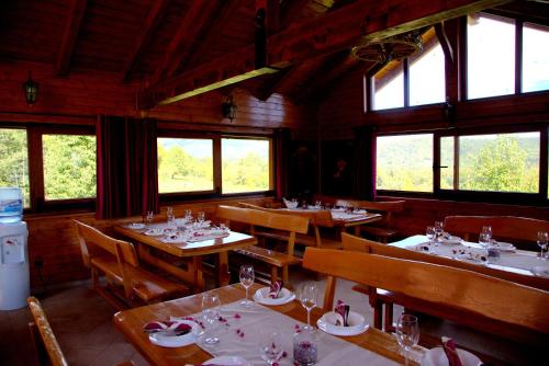 a dining room with tables and chairs and windows at Brezova Poljana Lodge in Vrbovsko