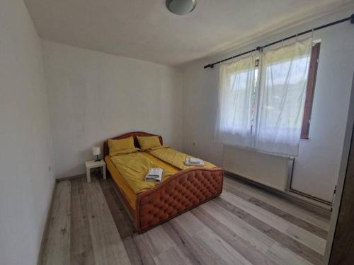 1 dormitorio con 1 cama con sábanas amarillas y ventana en Apartman Sofija en Banja Luka