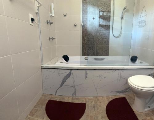 y baño con ducha, aseo y bañera. en Ville France: Chalé Bordeaux a 5 min do Centro, en Camanducaia