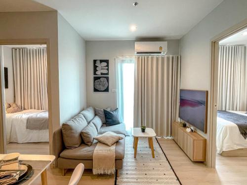 un salon avec un canapé et un lit dans l'établissement Srinakarin Lasalle 2 BR Bangkok, à Bangna