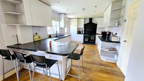 Una cocina con gabinetes blancos y encimeras negras. en 26 Woodgrove Drive, en Inverness