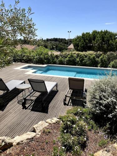 une piscine avec deux chaises et une table à côté dans l'établissement Grande Maison familiale Leucate vue mer et village, à Leucate
