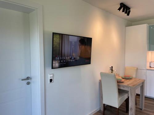 a dining room with a table and a tv on the wall at Jimmy's Place - Hotelgefühl, Tolle Lage, Terrasse, BBQ in Bad Zwischenahn