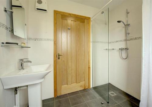 Kettleburgh的住宿－Akenfield Cottage, Letheringham，一间带水槽和玻璃门淋浴的浴室