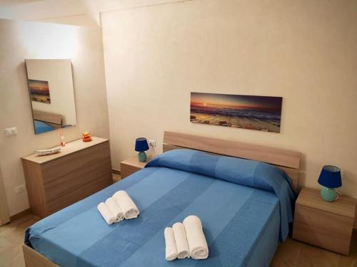 um quarto com uma cama azul e 2 toalhas brancas em Casa Elda em Marina di Ragusa