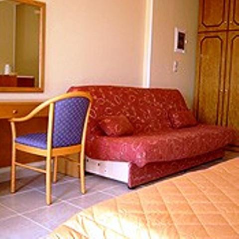 a chair and a red couch in a room at Eos Studios in Symi