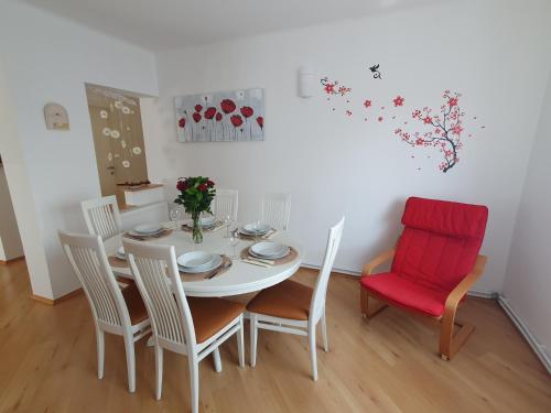 a dining room with a white table and a red chair at Apartment Sonata in Kamnik