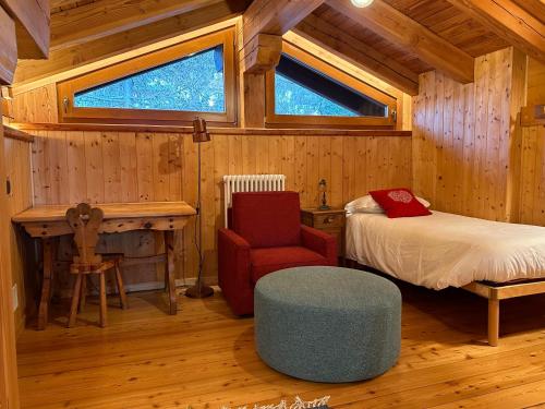 una camera con un letto e una sedia in una cabina di MaisonGorret a Valtournenche