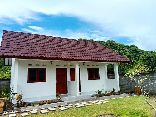 ein kleines weißes Haus mit einer roten Tür in der Unterkunft Singon LOMBOK homestay in Selong Belanak