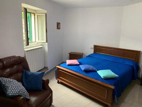 a bedroom with a bed with blue sheets and a couch at Alloggio Turistico A casa di Anna in Bagnoregio