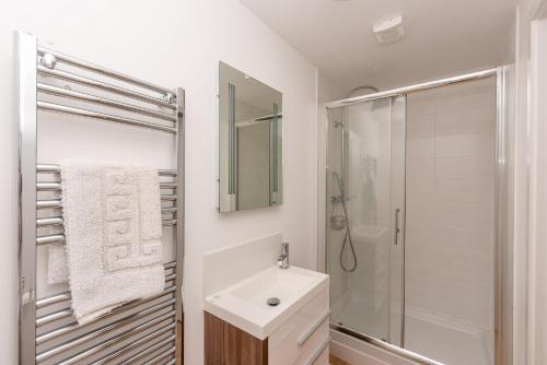 a white bathroom with a sink and a shower at Seashells in Woolacombe