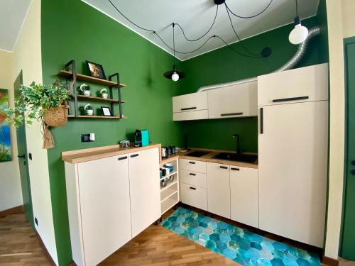 a kitchen with white cabinets and green walls at Urban Oasis in the Heart of Turin in Turin