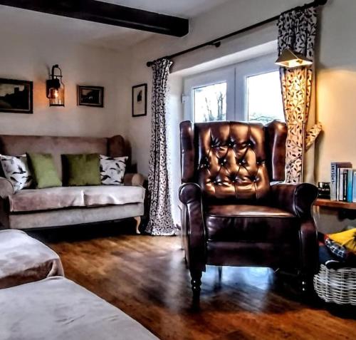- un salon avec un fauteuil en cuir et un canapé dans l'établissement Riverside Cottage, Helwith Bridge, Yorkshire Dales, à Horton in Ribblesdale