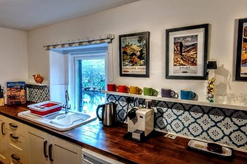 - un comptoir de cuisine avec un évier et des tasses au mur dans l'établissement Riverside Cottage, Helwith Bridge, Yorkshire Dales, à Horton in Ribblesdale