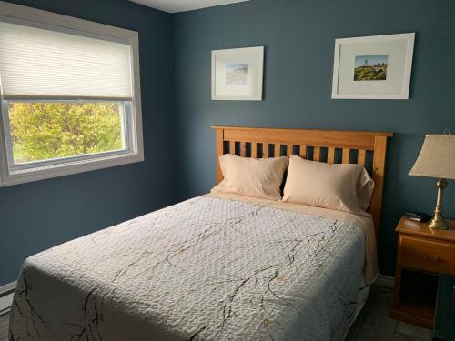 a bedroom with a bed with blue walls and a window at Legges Motel & Restaurant in Heartʼs Content