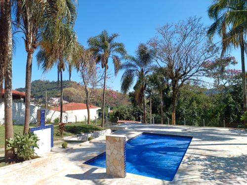 une piscine bleue avec des palmiers en arrière-plan dans l'établissement Chácara Rancho Fundo, à Águas de Lindóia