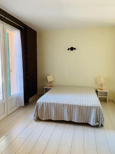 une chambre avec un lit et deux lampes et une fenêtre dans l'établissement Maison La Source, à Saint-Peïre-sur-Mer