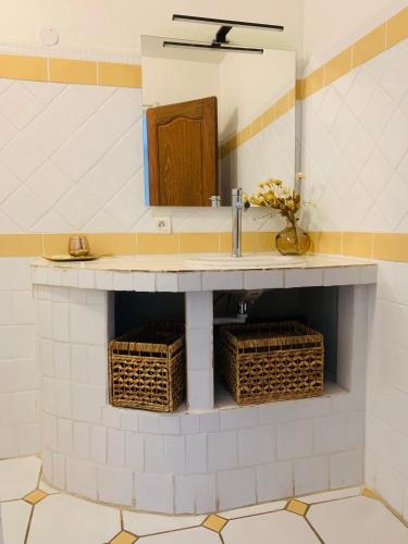 La salle de bains est pourvue d'un lavabo et de paniers en osier. dans l'établissement Maison La Source, à Saint-Peïre-sur-Mer