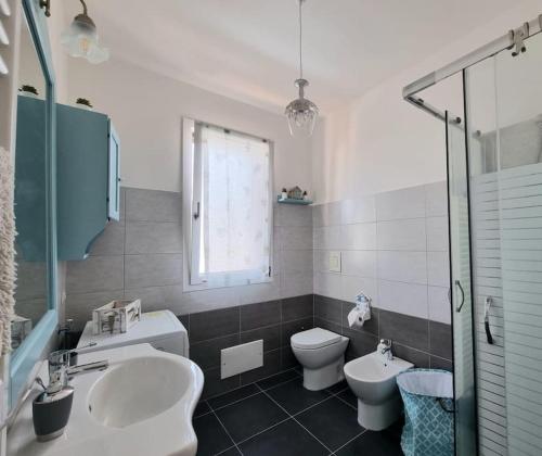 uma casa de banho com um lavatório, um WC e uma janela. em Flamingo's House in Sant'Antioco, Sardinia em SantʼAntìoco