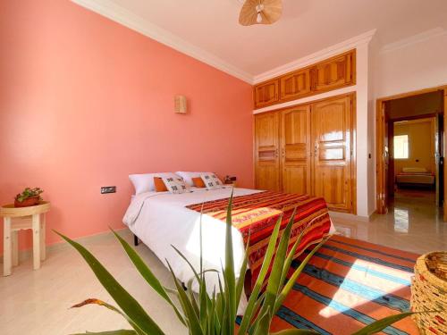 1 dormitorio con paredes rosas y 1 cama en Monkey's Guest House - Appartement roof top terrasse privée vue sur mer en Tamraght Ouzdar
