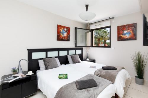 sypialnia z 2 łóżkami i oknem w obiekcie Luxury Garden apartment with stunning Cannes Marina views w mieście Mandelieu-la-Napoule