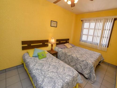 two beds in a room with yellow walls at La Hacienda San Felipe Condo 10 in San Felipe