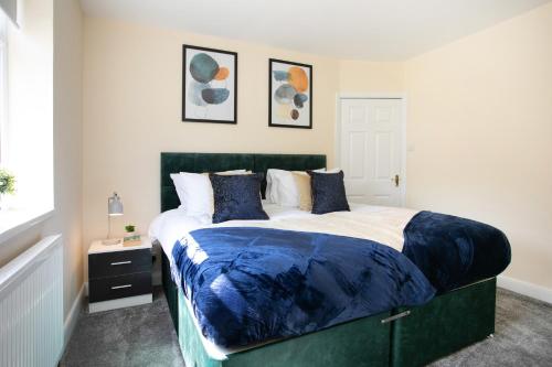 a bedroom with a large bed with blue sheets and pillows at Modern & Spacious House In Derby in Derby