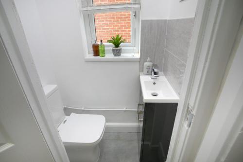 a bathroom with a toilet and a sink and a window at Modern & Spacious House In Derby in Derby