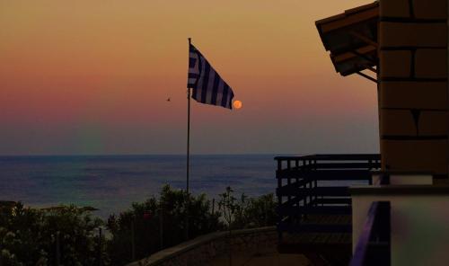 una bandiera di fronte all'oceano al tramonto di Villa Leonardo a Archangelos