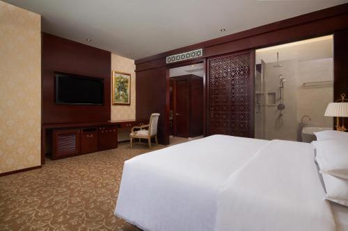 a hotel room with a white bed and a television at Sheraton Chongqing Hotel in Chongqing