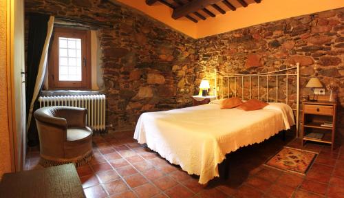 1 dormitorio con cama y pared de piedra en Bed and Breakfast Casanova de Sant Miquel, en Aiguafreda