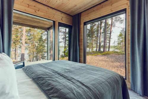 um quarto com uma cama grande e janelas grandes em Saunamäki Resort - State of the Art Coastal Villa em Salo