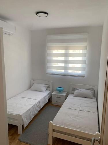 two twin beds in a room with a window at Sea's House in Bečići