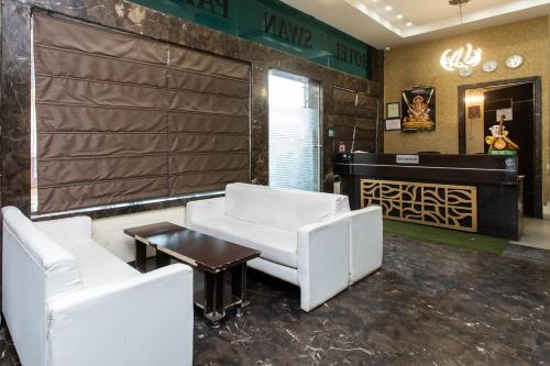 a lobby with two white chairs and a table at Capital O Swan Paradise in Indore