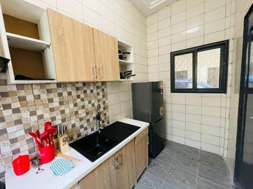 uma cozinha com um lavatório e um frigorífico preto em Appartement T 2 N°2: Résidence LES 11 PLURIELLES 