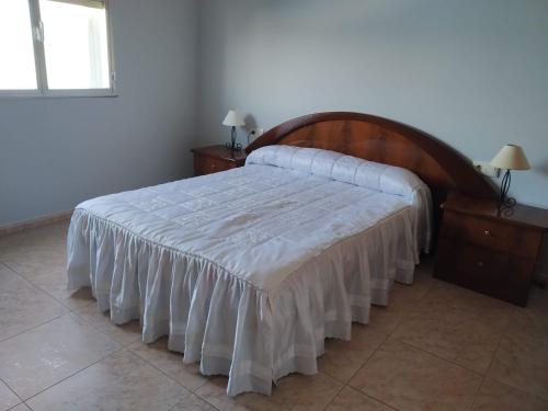- une chambre avec un grand lit et une tête de lit en bois dans l'établissement Pitis, à Bueu