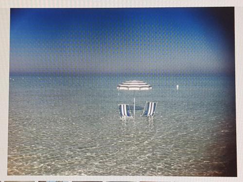 two chairs under an umbrella in the water at Zia Memè in Taviano