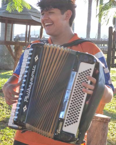 a young boy holding an accordion in a park at Contempla Joanópolis in Joanópolis
