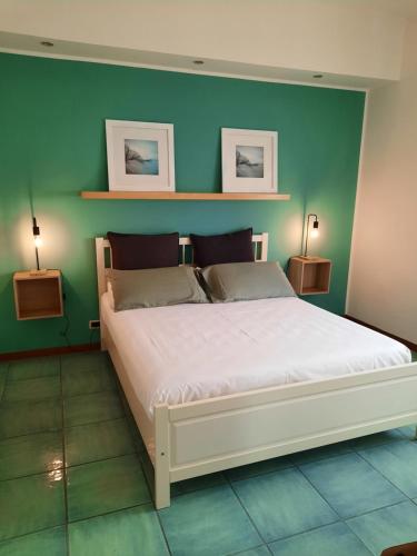 1 dormitorio con 1 cama blanca grande y paredes verdes en MARE FUORI APARTMENT en Civitavecchia
