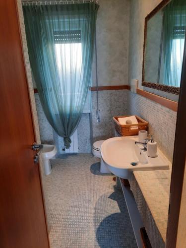 uma casa de banho com um lavatório, um WC e um espelho. em MARE FUORI APARTMENT em Civitavecchia