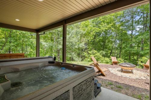 a hot tub on a patio with a view of the woods at Stunning Views, Superb Atmosphere, Modern Amenities, In the Middle of Nature in Bryson City