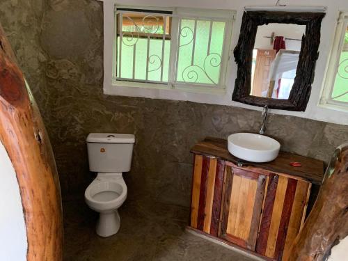 a bathroom with a toilet and a sink and a mirror at Hillstone Safari Lodge in Kimana