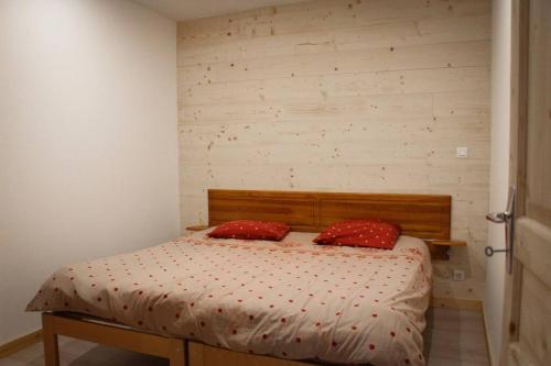 um quarto com uma cama com duas almofadas vermelhas em L'Écrin - Appartement au pied des pistes em Orcières