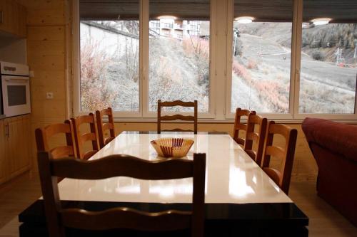 tavolo da pranzo e sedie di fronte a una finestra di L'Écrin - Appartement au pied des pistes a Orcières