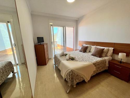 een grote slaapkamer met een bed en een televisie bij Costa Adeje Sunset Apartment in Adeje