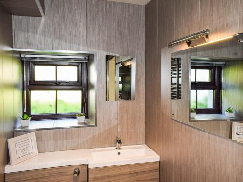 a bathroom with a sink and two mirrors at The Studio At Malt Kiln Cottage in Grizebeck