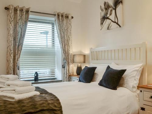 a bedroom with a white bed with pillows and a window at The Alnwick Townhouse in Alnwick